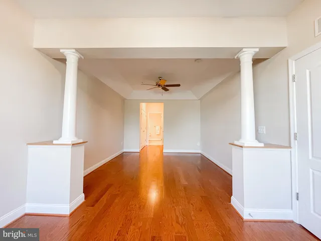 a view of empty room with wooden floor and fan