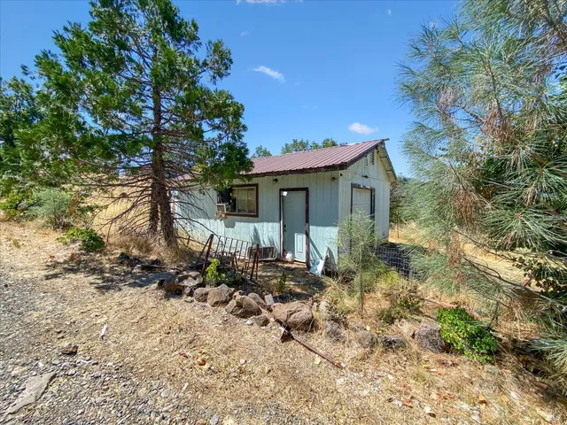 a backyard of a house with table and chairs under an umbrella