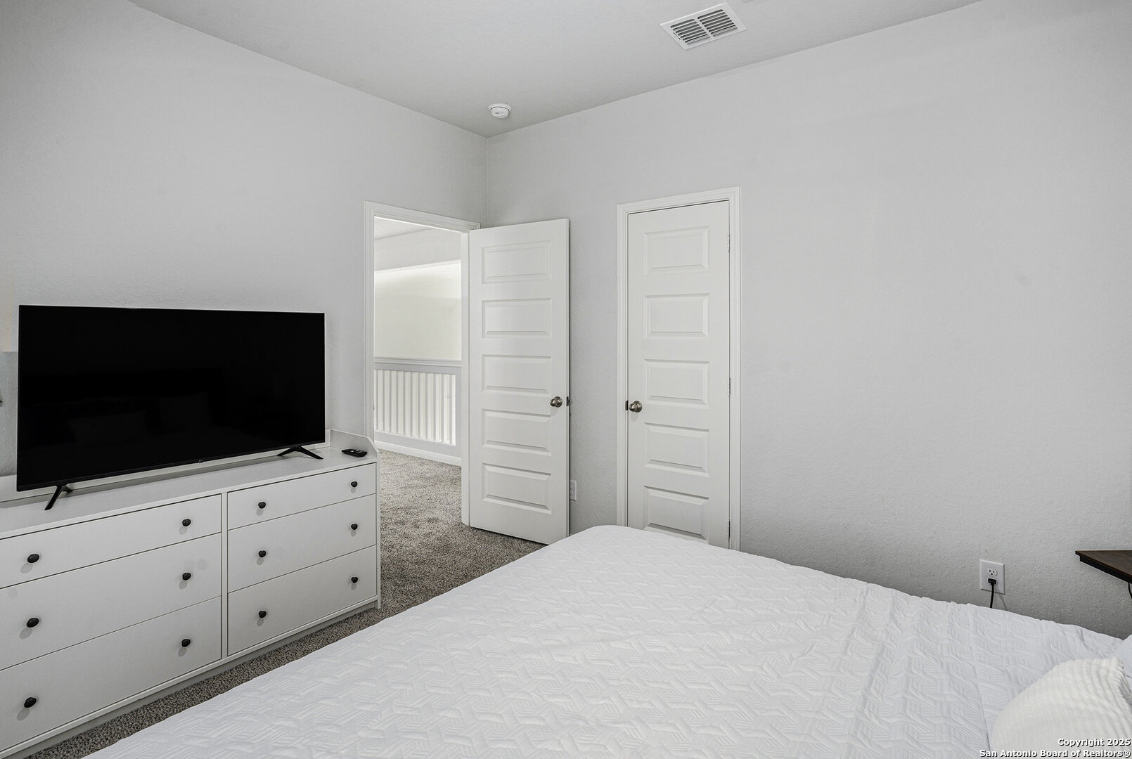 16615 Ginger Crossing Elmendorf, TX 78112 - Photo 23 of 31 a bedroom with a bed and a flat screen tv in white wall
