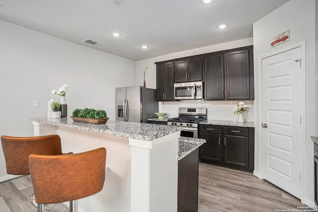 a kitchen with kitchen island granite countertop stainless steel appliances stove microwave refrigerator and cabinets