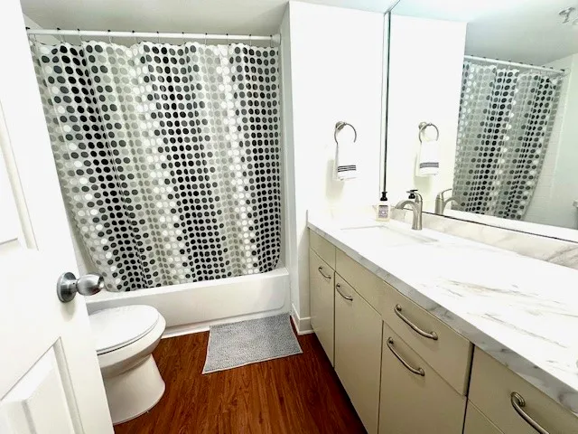 a bathroom with a granite countertop sink a toilet a mirror and shower
