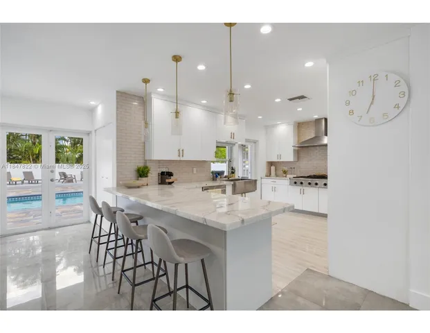 a kitchen with stainless steel appliances kitchen island granite countertop a sink a stove a dining table and chairs