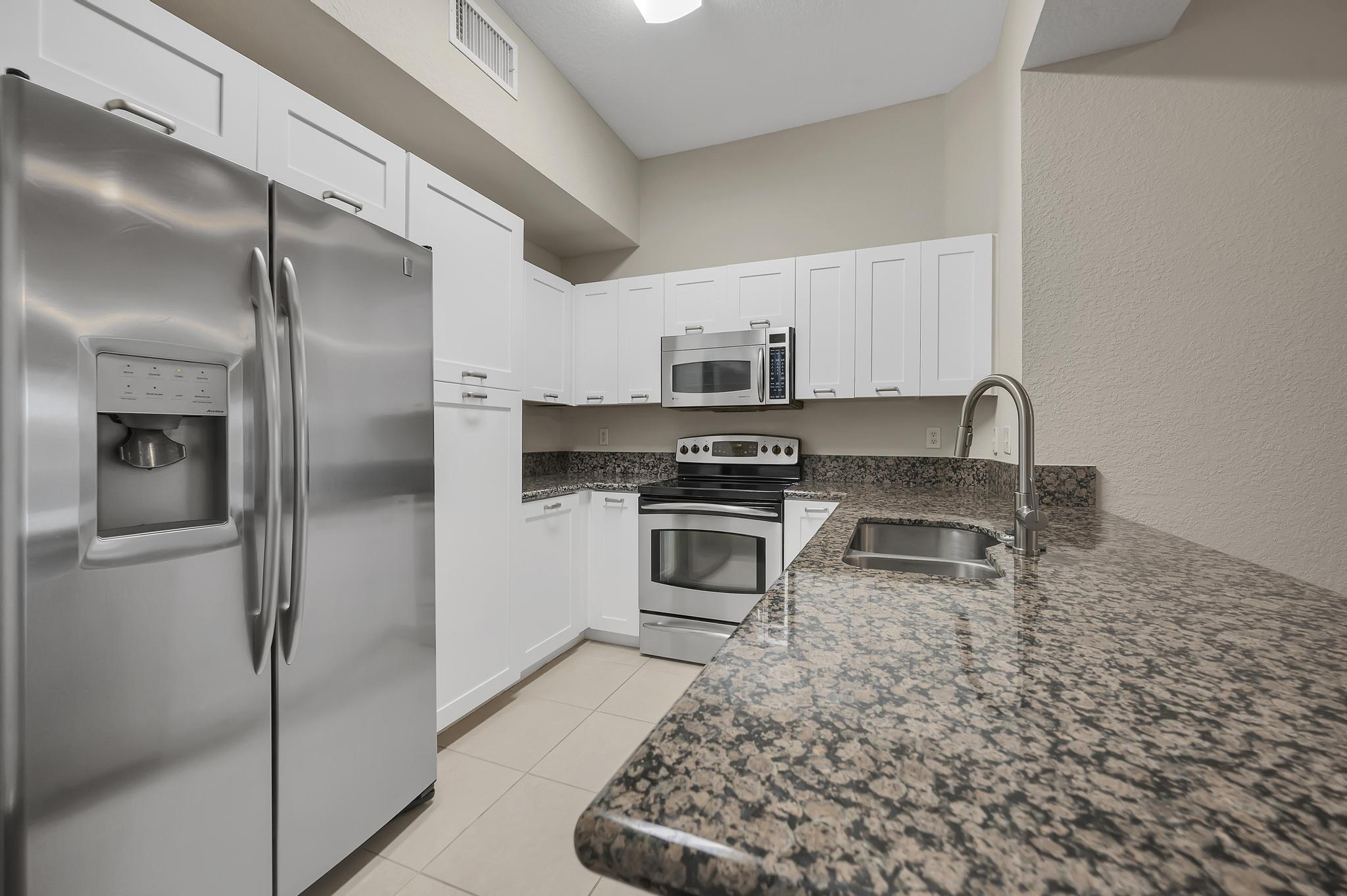55 Southeast Palermo, Unit 106 Stuart, FL 34994 - Photo 5 of 39 a kitchen with stainless steel appliances granite countertop a refrigerator a stove and a sink