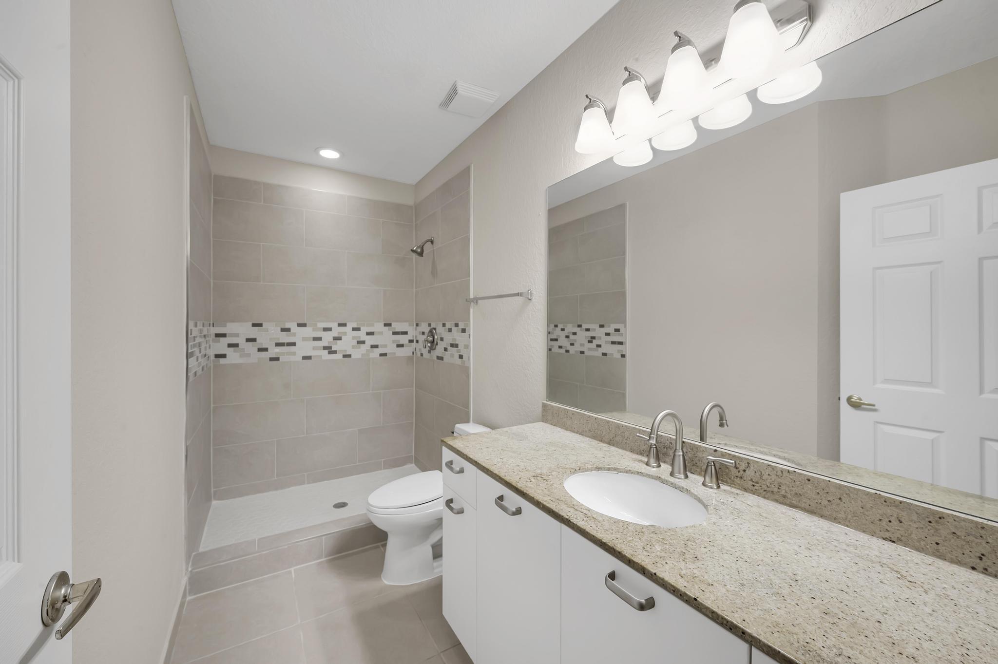 55 Southeast Palermo, Unit 106 Stuart, FL 34994 - Photo 10 of 39 a bathroom with a granite countertop sink a toilet and a mirror