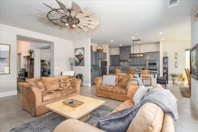 a living room with furniture kitchen view and a chandelier