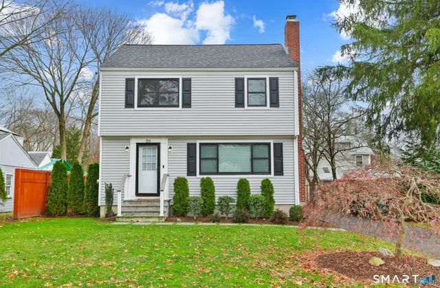a front view of a house with a garden and trees