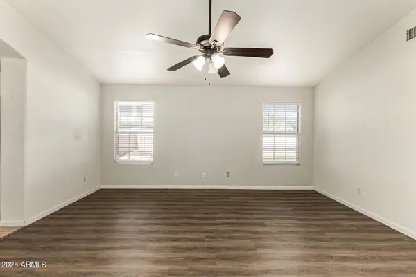an empty room with wooden floor fan and windows