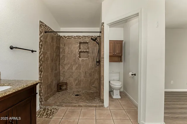 a bathroom with a granite countertop shower a toilet and a sink
