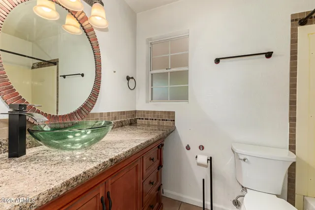 a bathroom with a granite countertop sink a toilet and a mirror