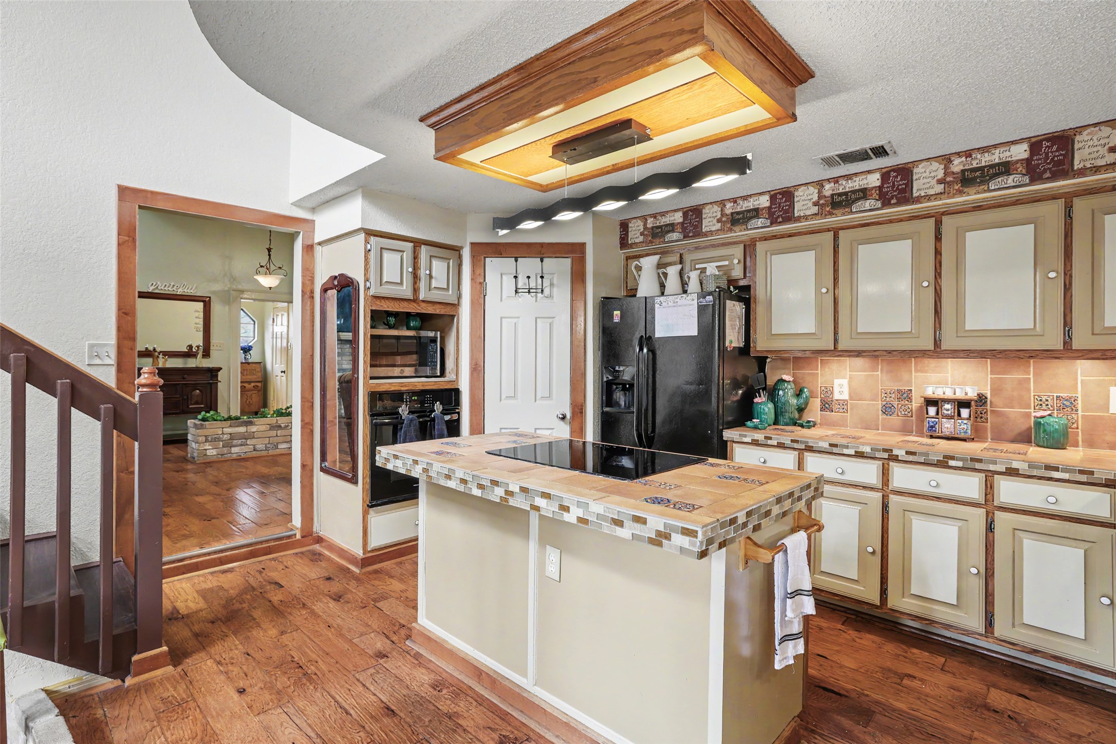 110 South Ridge Circle Georgetown, TX 78628 - Photo 13 of 37 Kitchen featuring wood-finish flooring, an island with a tile-finish countertop, integrated cooktop, and built-in wall oven with microwave