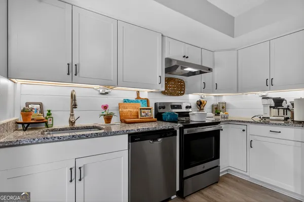 a kitchen with stainless steel appliances granite countertop a sink a stove and cabinets