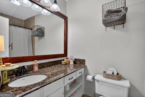 a bathroom with a granite countertop sink a mirror and a toilet