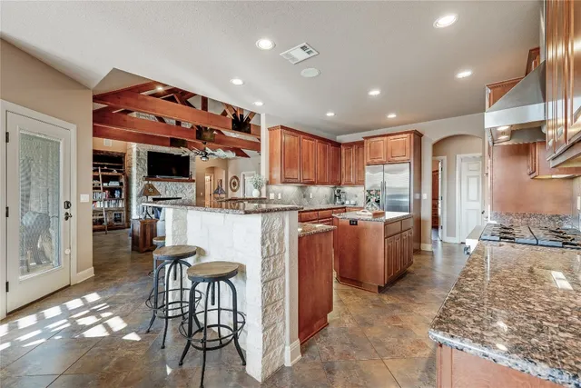 a kitchen with stainless steel appliances granite countertop a refrigerator and a stove top oven with wooden floor
