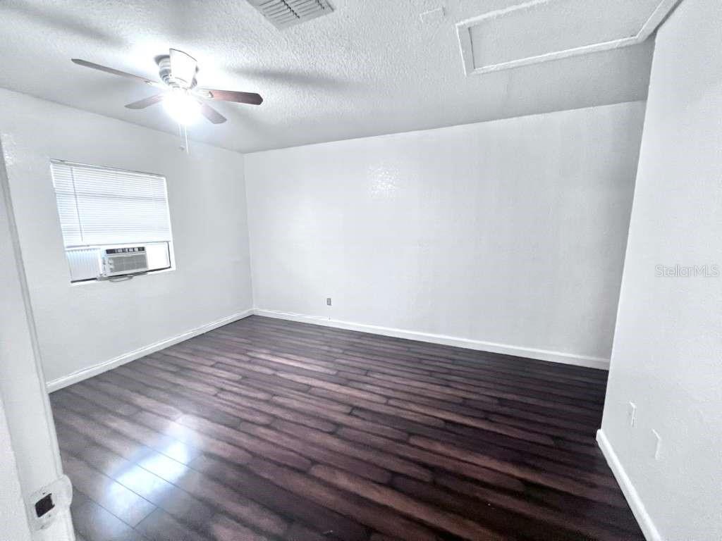 3409 Vorden Street New Port Richey, FL 34655 - Photo 24 of 41 an empty room with wooden floor chandelier fan and windows