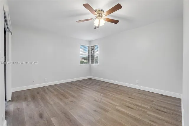 an empty room with wooden floor closet and fan