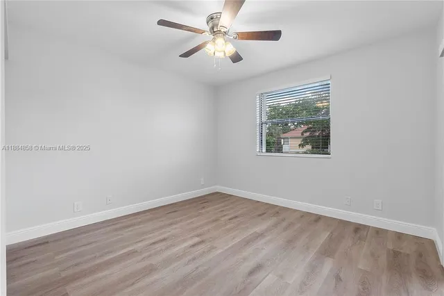 a view of a room with wooden floor and a ceiling fan