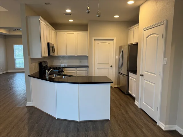 a kitchen with stainless steel appliances a refrigerator stove and wooden floor