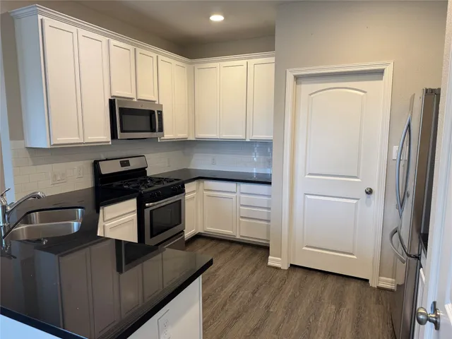 a kitchen with white cabinets and black appliances