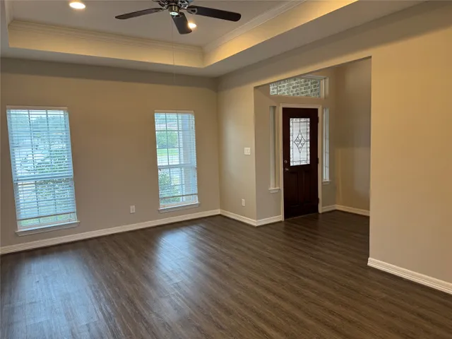 an empty room with wooden floor chandelier fan and windows