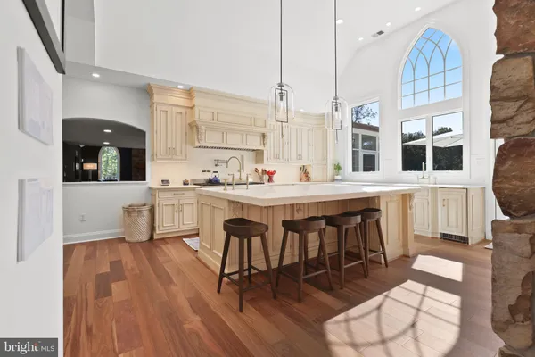 a dining hall with stainless steel appliances kitchen island granite countertop a dining table chairs and a living room view