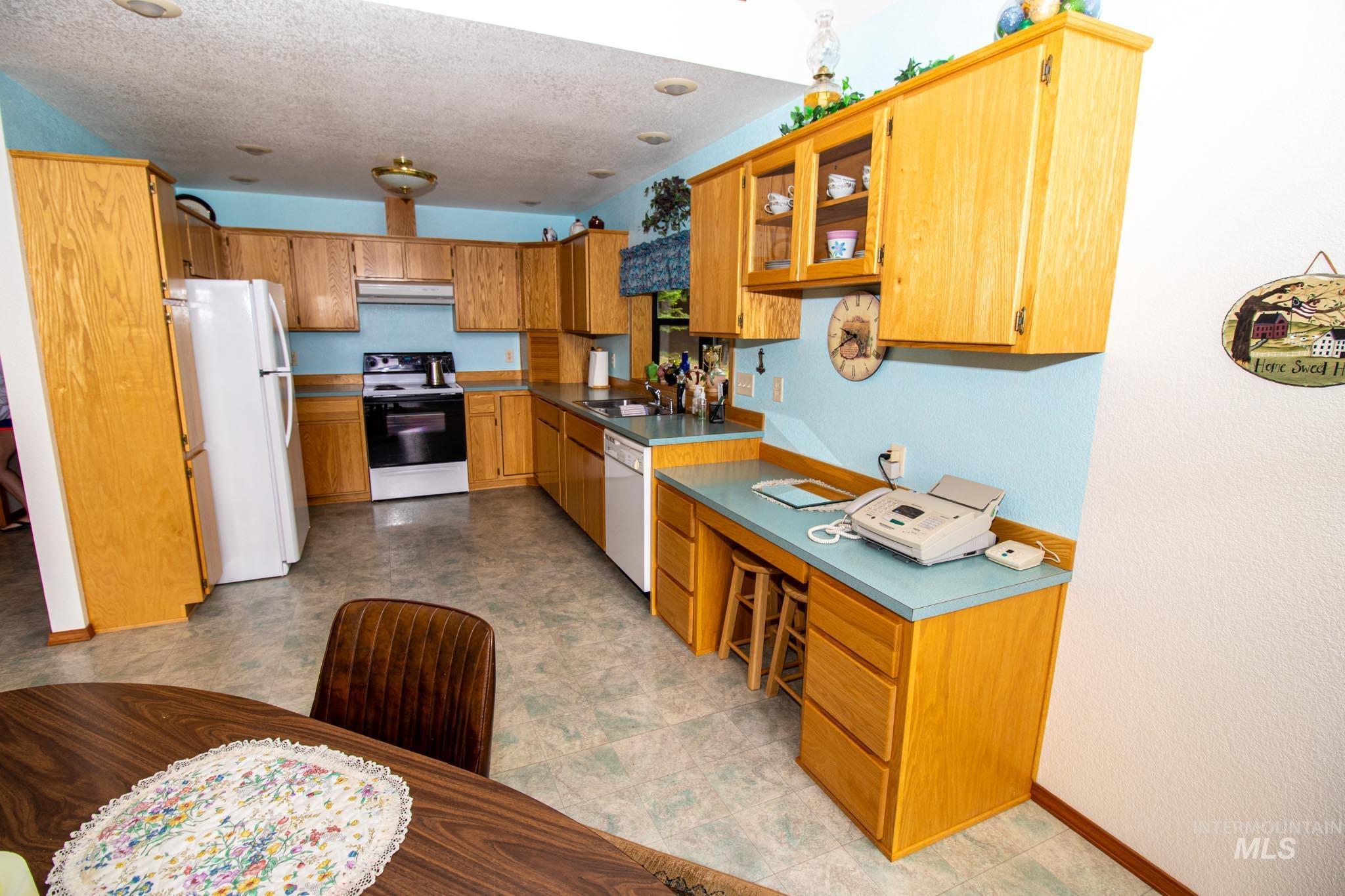 20888 Upper Fords Creek Road Weippe, ID 83553 - Photo 14 of 50 Kitchen with white appliances, a textured ceiling, wood finish cabinets, light floors, and a textured wall