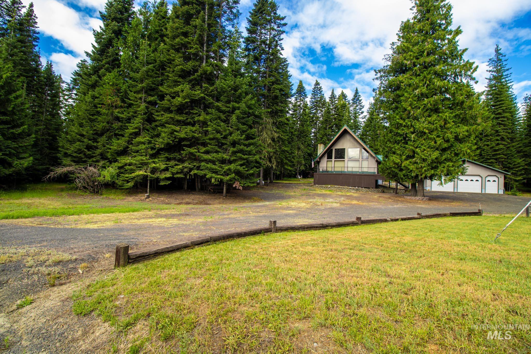 20888 Upper Fords Creek Road Weippe, ID 83553 - Photo 47 of 50 View of green lawn with view of wooded area and a garage