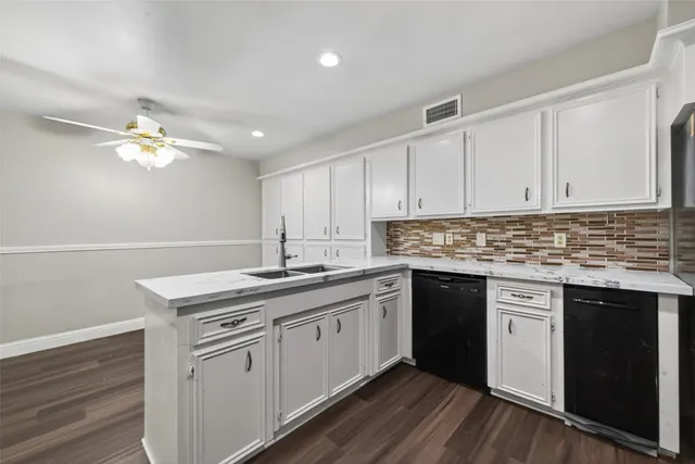 a kitchen with stainless steel appliances granite countertop a sink dishwasher a stove and white cabinets with wooden floor