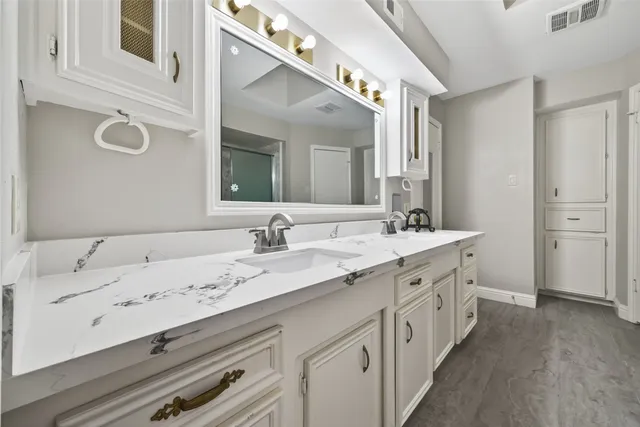 a bathroom with a granite countertop double vanity sink and mirror