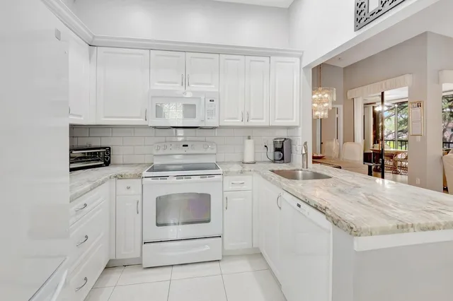 a kitchen with granite countertop white cabinets and white appliances