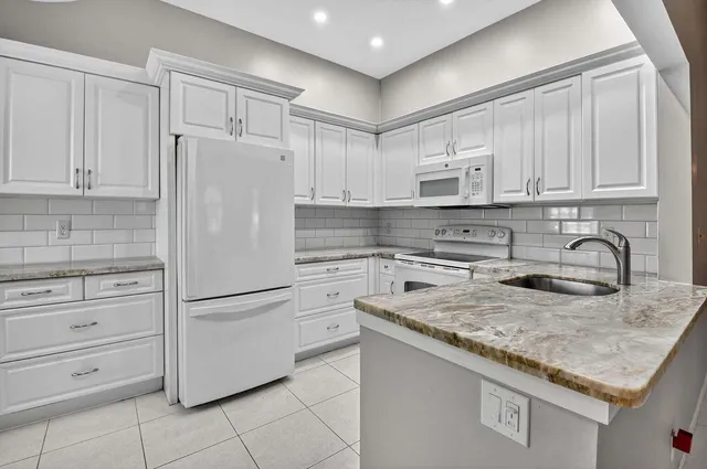 a kitchen with white cabinets stainless steel appliances and sink