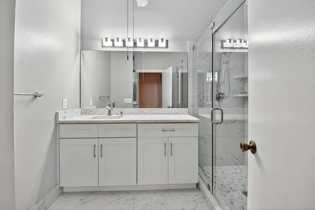 a bathroom with a granite countertop sink a mirror and shower