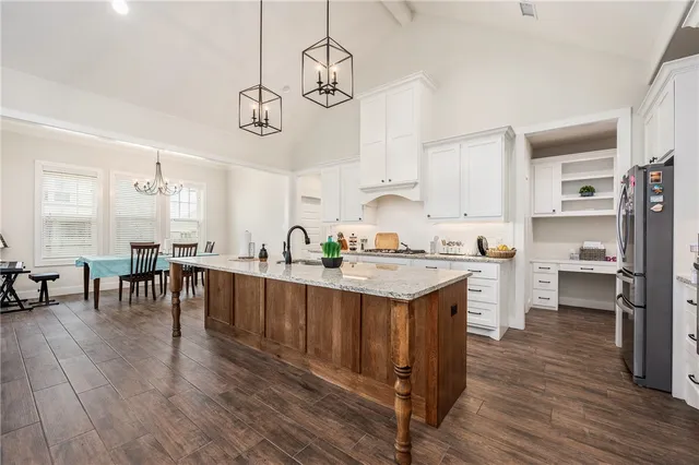 a open kitchen with stainless steel appliances granite countertop a sink a stove and chairs with wooden floor