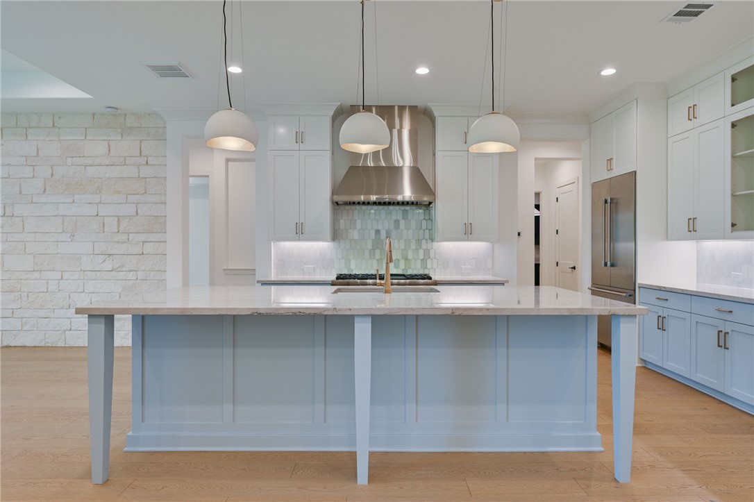 5115 Inverness Drive Bryan, TX 77802 - Photo 6 of 28 Kitchen featuring a large central island with a light blue finish, light wood-finish flooring, white upper cabinetry, light blue lower cabinetry, and stainless steel appliances
