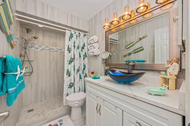 a bathroom with a granite countertop sink a toilet and shower