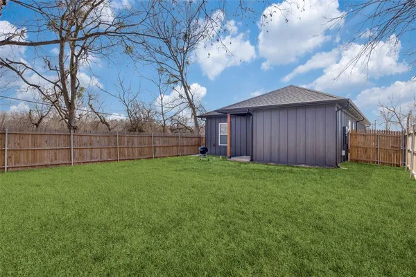 a view of a backyard with wooden fence and a large tree