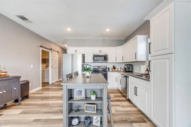 a large kitchen with stainless steel appliances granite countertop a stove and white cabinets