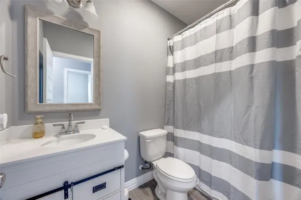 a bathroom with a sink a toilet a mirror and shower curtain
