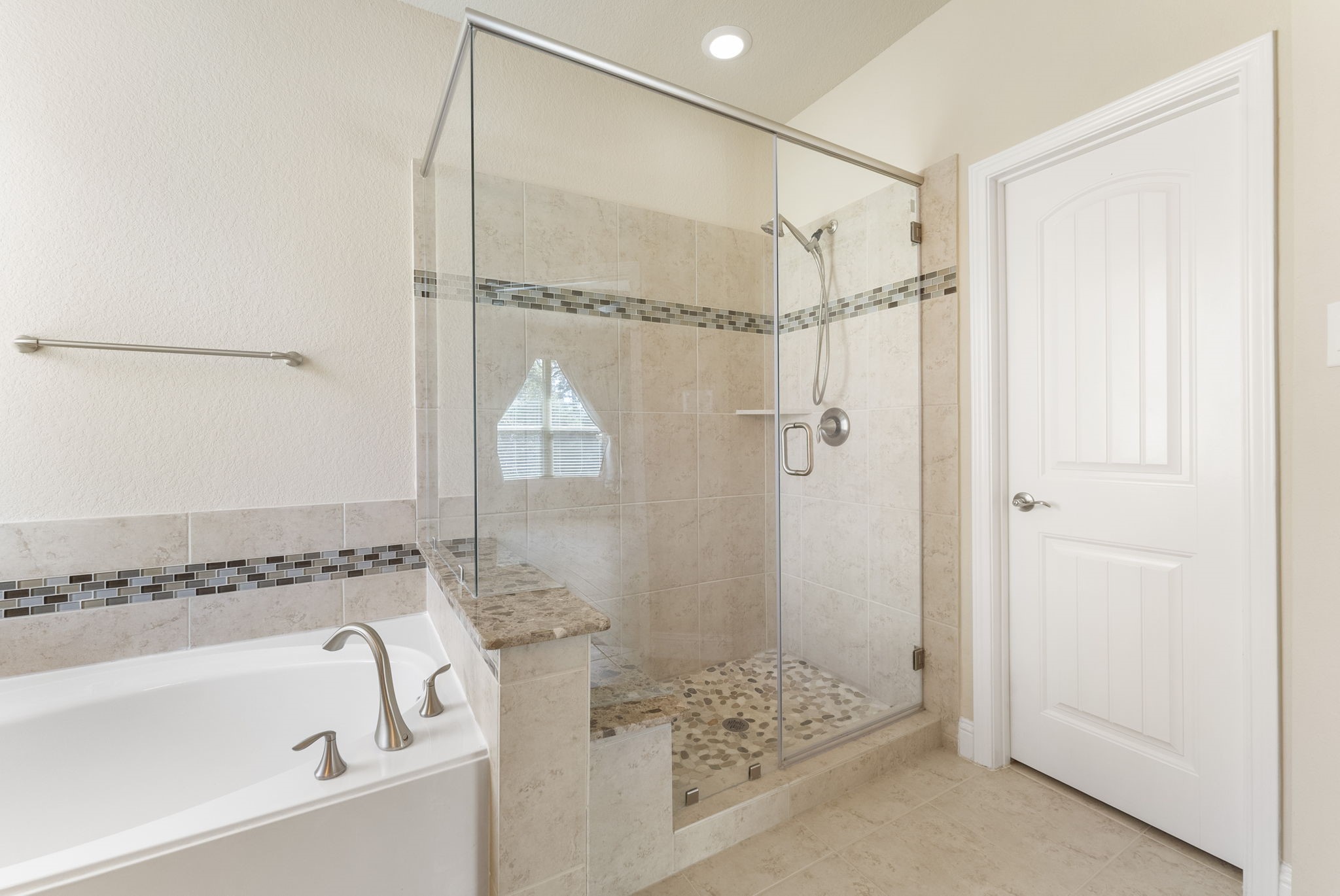 3565 Falcon Way Conroe, TX 77304 - Photo 22 of 50 Glass-enclosed primary shower with built-in bench and decorative tile accents.