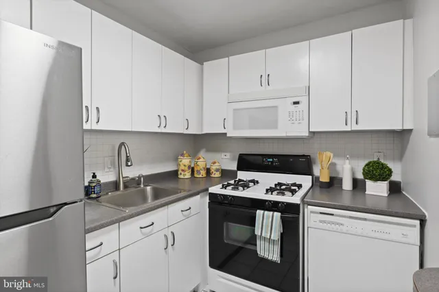 a kitchen with granite countertop white cabinets and white appliances