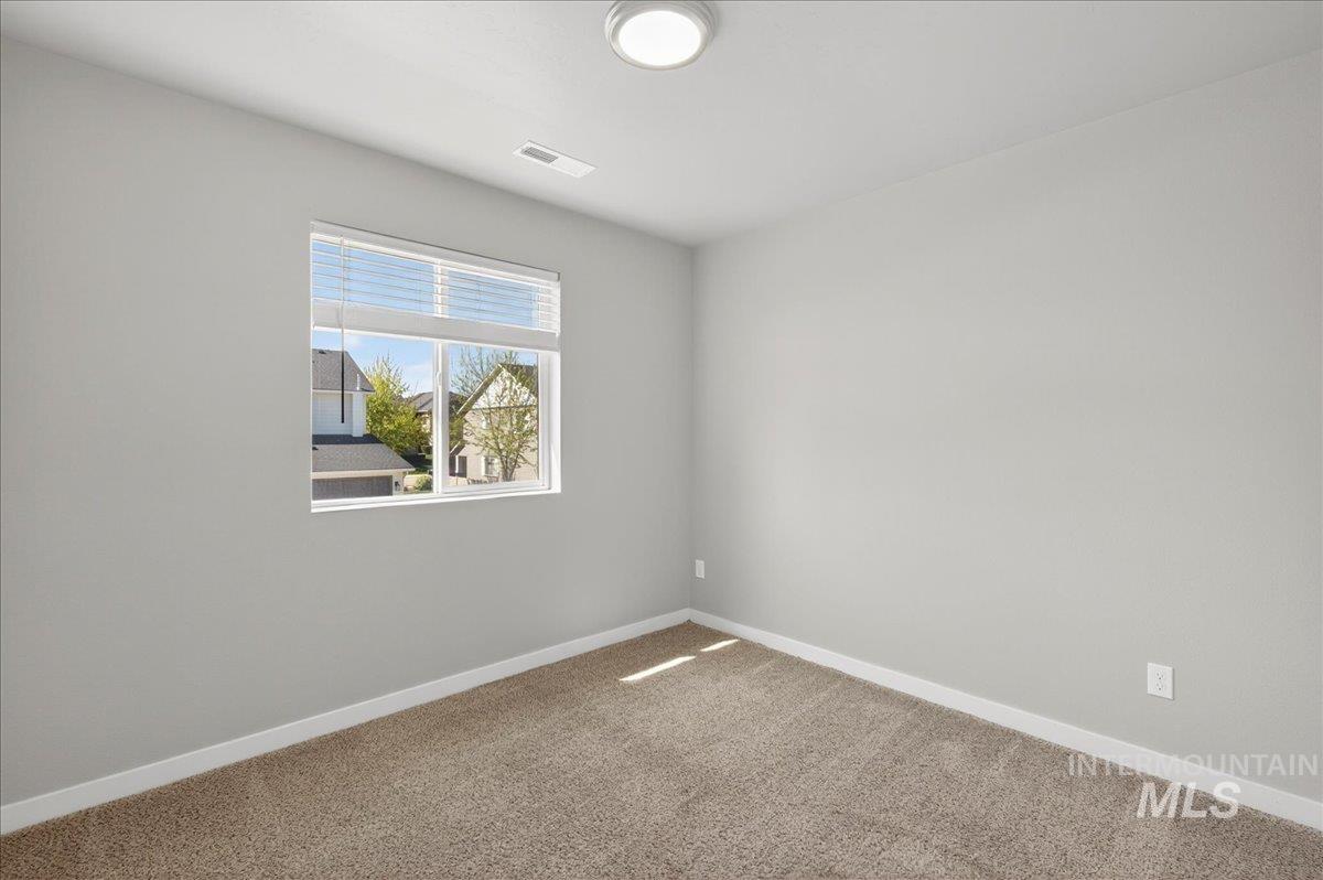 2505 East Goldstone Street Meridian, ID 83642 - Photo 13 of 28 Neutral-toned room featuring a large window with blinds, light gray walls, white baseboards, and carpeted flooring