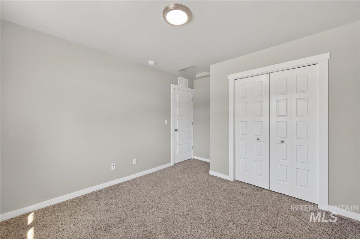 2505 East Goldstone Street Meridian, ID 83642 - Photo 15 of 28 Neutral wall color, plush carpeting, white baseboards, a built-in closet with paneled bifold doors, and a flush-mount ceiling light fixture