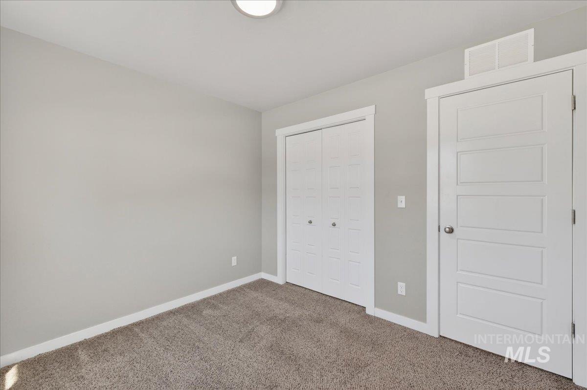 2505 East Goldstone Street Meridian, ID 83642 - Photo 16 of 28 Neutral-toned wall paint, modern white trim, and a textured carpeted floor