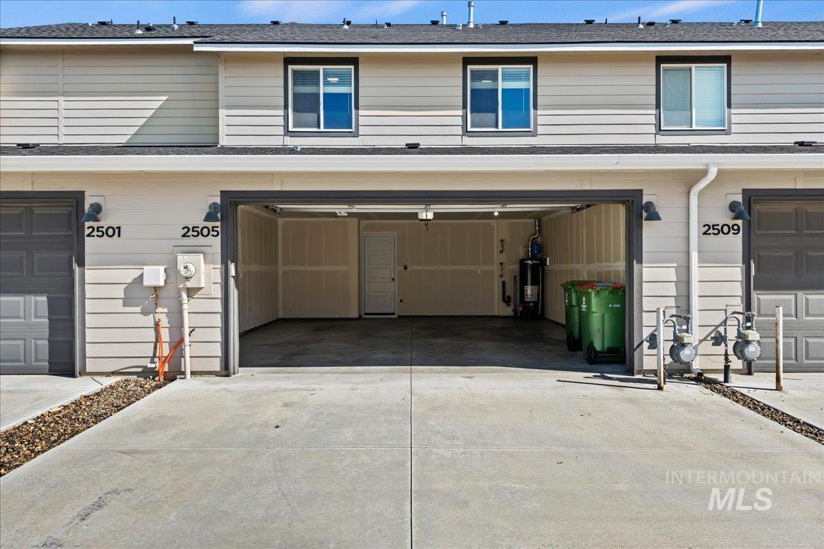 2505 East Goldstone Street Meridian, ID 83642 - Photo 24 of 28 Integrated garage with concrete driveway, light beige horizontal siding, black-framed windows, and exterior wall sconces