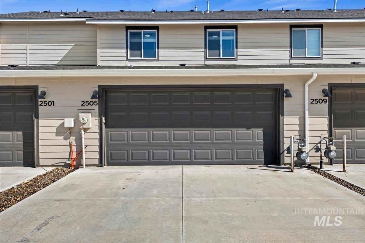 2505 East Goldstone Street Meridian, ID 83642 - Photo 25 of 28 Townhome exterior featuring a two-car garage with a panel door, concrete driveway, horizontal siding, and dark-framed windows