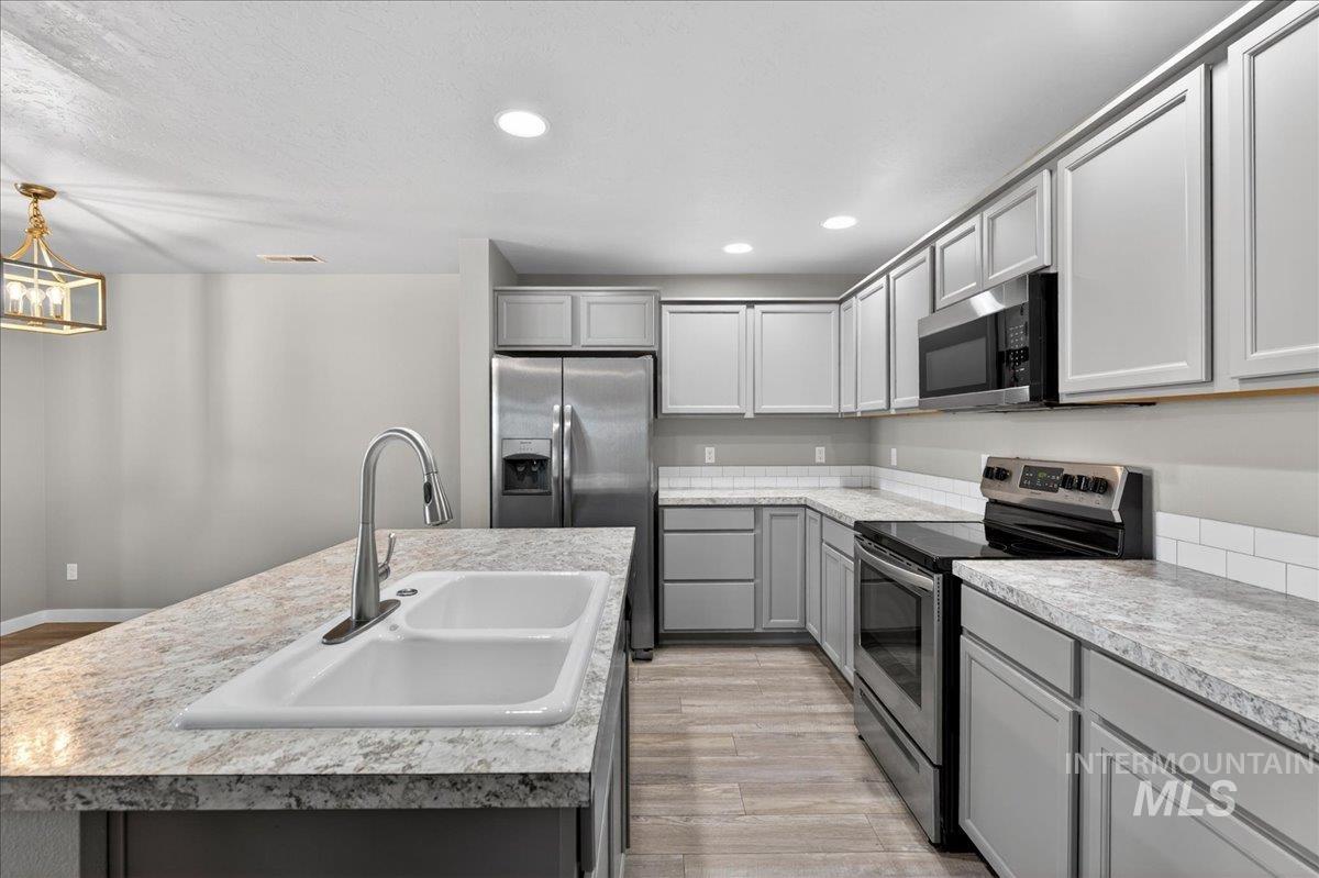 2505 East Goldstone Street Meridian, ID 83642 - Photo 9 of 28 Modern kitchen featuring light gray cabinetry, stainless steel appliances, and a white subway tile backsplash
