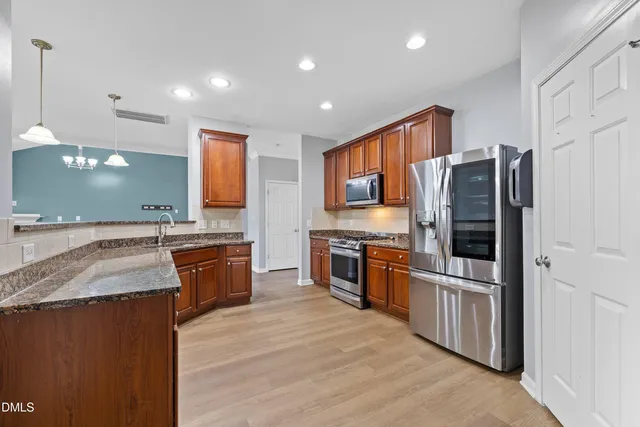 a large kitchen with granite countertop a large counter top stainless steel appliances and cabinets