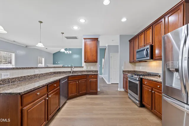 a large kitchen with stainless steel appliances granite countertop a stove a sink dishwasher a refrigerator and a oven