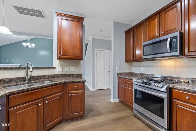 a kitchen with stainless steel appliances granite countertop a stove microwave and cabinets