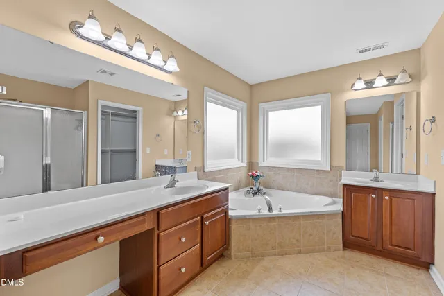a spacious bathroom with a bathtub double sink and mirror
