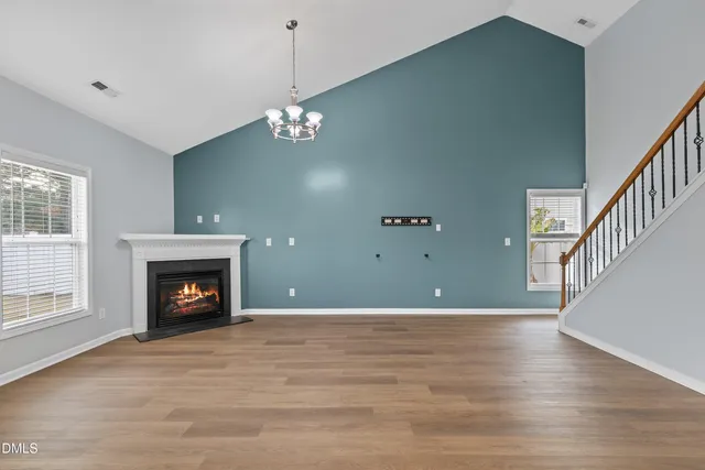 a view of an empty room with wooden floor fireplace and a window